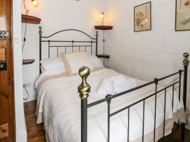 A bedroom with a metal bed frame white bedding rolled towels and wall art at The Dairy Carrog near Corwen