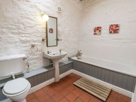 A bathroom with a toilet sink bathtub mirror and two paintings on the wall at The Dairy in Carrog near Corwen