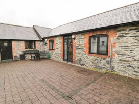 A brick paved courtyard with stone and brick walls and black framed windows at The Dairy in Carrog near Corwen