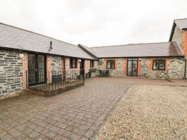 An outdoor courtyard with stone and brick buildings and patio furniture at The Dairy in Carrog near Corwen
