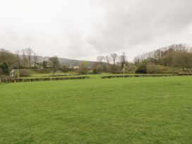 A grassy field with trimmed hedges and trees in the background at The Dairy in Carrog near Corwen