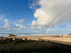 A beach view with a rainbow and clouds at Saltwater, One Lusty Glaze Newquay