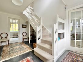 A hallway with stairs and chairs at Kilcarreg in Rock near Wadebridge