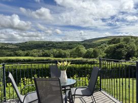 A balcony with table and chairs overlooking hills at Llaethdy - The Dairy Boncath near Crymych