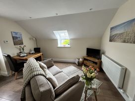 A living room with a sofa and dining table at Lloft Gwair - Hayloft Boncath near Crymych