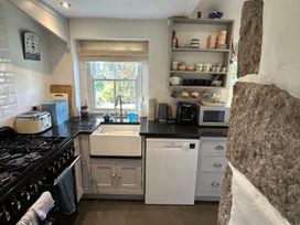 A kitchen with a sink, stove, and storage shelves at 14 Boscaswell Downs Pendeen near St Just