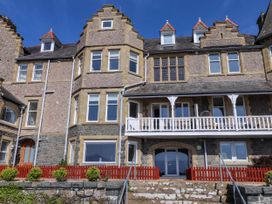 The exterior of a multi-story stone house with multiple windows a balcony and a red wooden fence near Menai Bridge