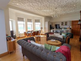 An open plan living room and kitchen with sofas pillows dining table and chandelier at Menai View near Menai Bridge