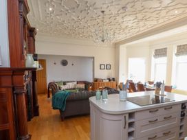 An open living and dining area with a kitchen island and a wooden fireplace at Menai View near Menai Bridge