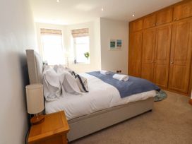 A bedroom with a bed a wooden nightstand and a large wooden wardrobe near Menai Bridge