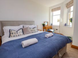 A bedroom with a bed with blue cover and white towels with a vanity table and two windows at Menai View near Menai Bridge