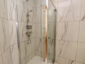 A shower area with marble patterned tiles and a glass door at Menai View near Menai Bridge