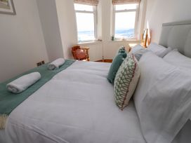 A bed with pillows and rolled towels near two windows and a wooden chair at Menai View near Menai Bridge