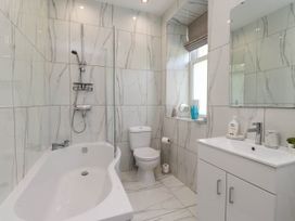 A bathroom with a bathtub shower combination a toilet and a sink with cabinet at Menai View near Menai Bridge