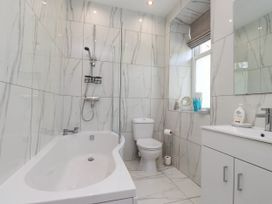 A bathroom with a bathtub shower toilet sink and cabinet at Menai View near Menai Bridge