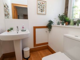 A bathroom with a pedestal sink, a toilet, plants on the windowsill, and artwork on the wall at Menai View near Menai Bridge