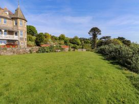 A large grassy garden area with benches and trees beside a stone building at Menai View near Menai Bridge