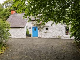 A cottage with a blue door and gravel driveway at Rosslare Cottage in Broughshane