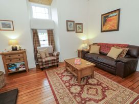 A living room with a sofa and armchair at Rosslare Cottage in Broughshane