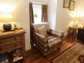 A living room with an armchair and a lamp at Rosslare Cottage Broughshane