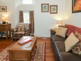 A living room with a sofa and armchair at Rosslare Cottage in Broughshane