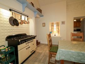 A kitchen with a stove and dining table at Rosslare Cottage in Broughshane