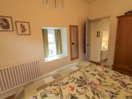 A bedroom with a bed, window, and wooden wardrobe at Rosslare Cottage, Broughshane