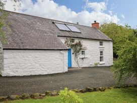 A cottage with a blue door and solar panels at Rosslare Cottage in Broughshane