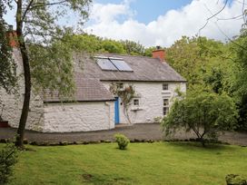 A cottage with a garden and trees at Rosslare Cottage in Broughshane