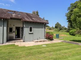 An outdoor view of a building with a patio and grass at Yew - Woodland Cottages Bowness-On-Windermere