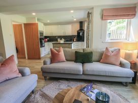 A living room with a sofa and kitchen area at Yew - Woodland Cottages Bowness-On-Windermere