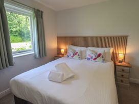 A bedroom with a double bed and bedside table at Yew - Woodland Cottages Bowness-On-Windermere