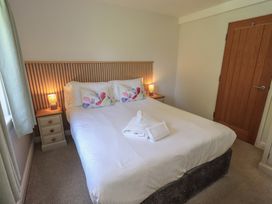 A bedroom with bed and bedside table at Yew - Woodland Cottages in Bowness-On-Windermere