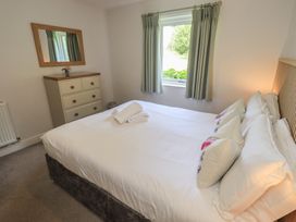 A bedroom with a bed and dresser at Yew - Woodland Cottages Bowness-On-Windermere