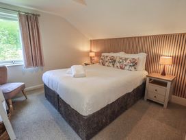 A bedroom with a bed, bedside tables, and a window at Yew - Woodland Cottages in Bowness-On-Windermere
