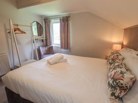 A bedroom with a bed and a mirror at Yew - Woodland Cottages in Bowness-On-Windermere