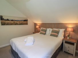 A bedroom with a bed and bedside table at Yew - Woodland Cottages, Bowness-On-Windermere