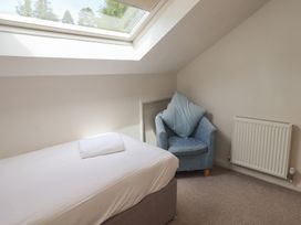 A bedroom with a bed and armchair at Yew - Woodland Cottages, Bowness-On-Windermere