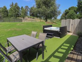 A garden with a table and chairs next to a hot tub at Yew - Woodland Cottages in Bowness-On-Windermere
