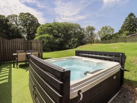 A hot tub with a table and chairs in a garden at Yew - Woodland Cottages Bowness-On-Windermere