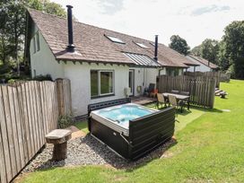 An outdoor area with a hot tub and seating at Yew - Woodland Cottages Bowness-On-Windermere