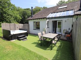 An outdoor area with a hot tub and dining table at Yew - Woodland Cottages Bowness-On-Windermere