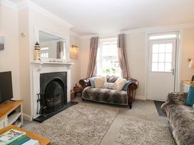 A living room with a fireplace and a television at Fern Cottage in Heacham