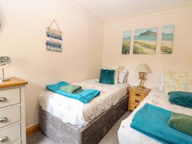 A bedroom with two beds and a bedside table at Fern Cottage Heacham