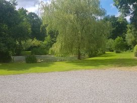 A garden with a pond and trees at The Barn at Waunlippa in Narberth