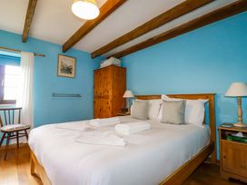 A bedroom with a bed, chair, and wardrobe at 4 Mowhay Cottages Gorran Haven