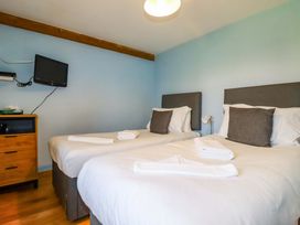 A bedroom with two beds and a television at 4 Mowhay Cottages in Gorran Haven