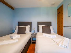 A bedroom with two beds and a bedside table at 4 Mowhay Cottages Gorran Haven