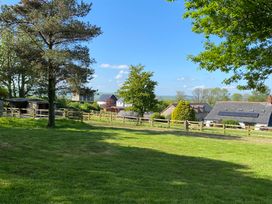 A grassy yard with trees fences and houses in the background at Oak Cottage in Bryngwenith near Newcastle Emlyn
