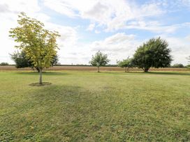 A grassy area with trees and a field at The Annexe in Litcham
